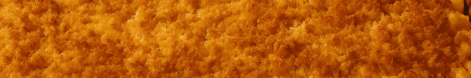 A wide pan of smoked mac and cheese with a golden panko crust resting on a wooden table next to a backyard smoker.